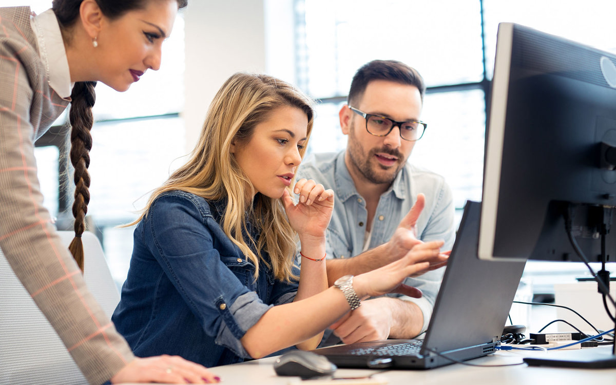 training three people overlooking one laptop in discussion