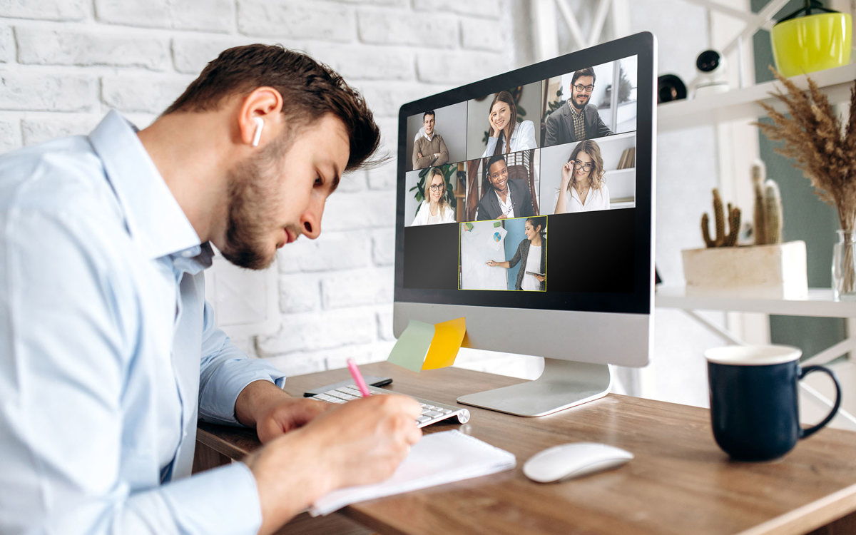 training man writing notes whilst on a video call with 7 others