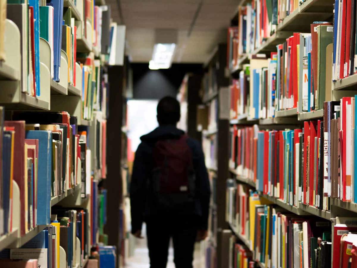 school-environment someone walking past filled book shelves