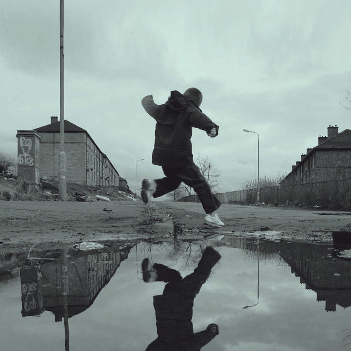Black and white photo of child jumping over puddle