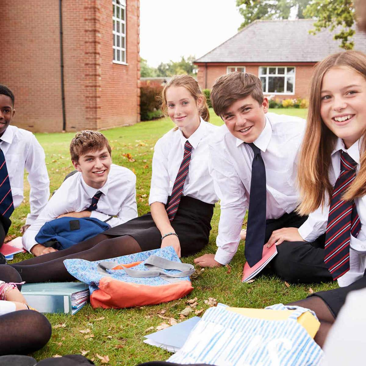 Pupils-learning smiling pupils outside sitting down on grass