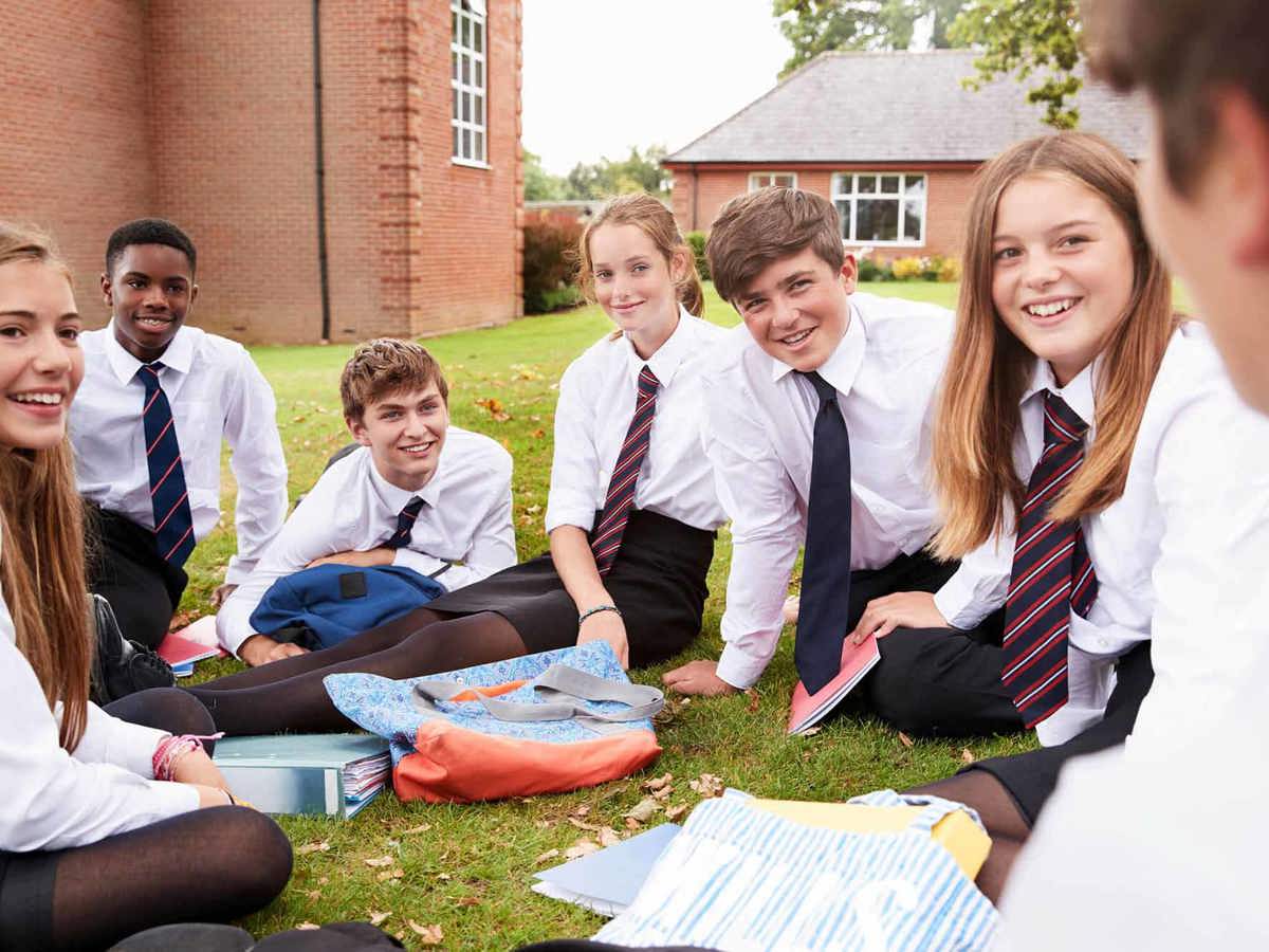 Pupils-learning smiling pupils outside sitting down on grass