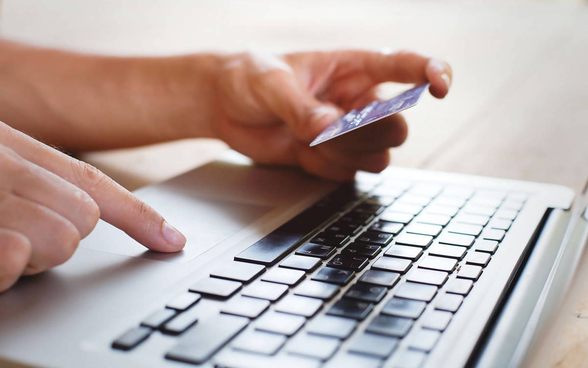 training someone using laptop whilst holding a bank card