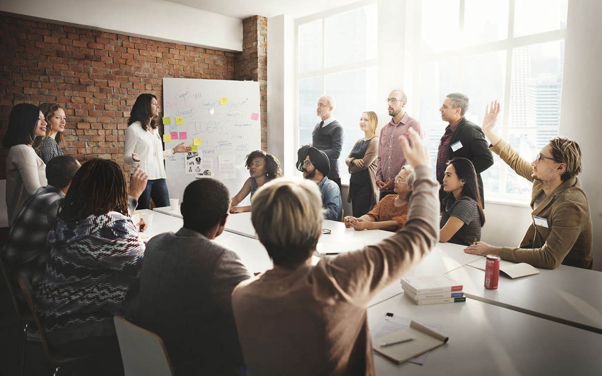 people raising their hands in a meeting room