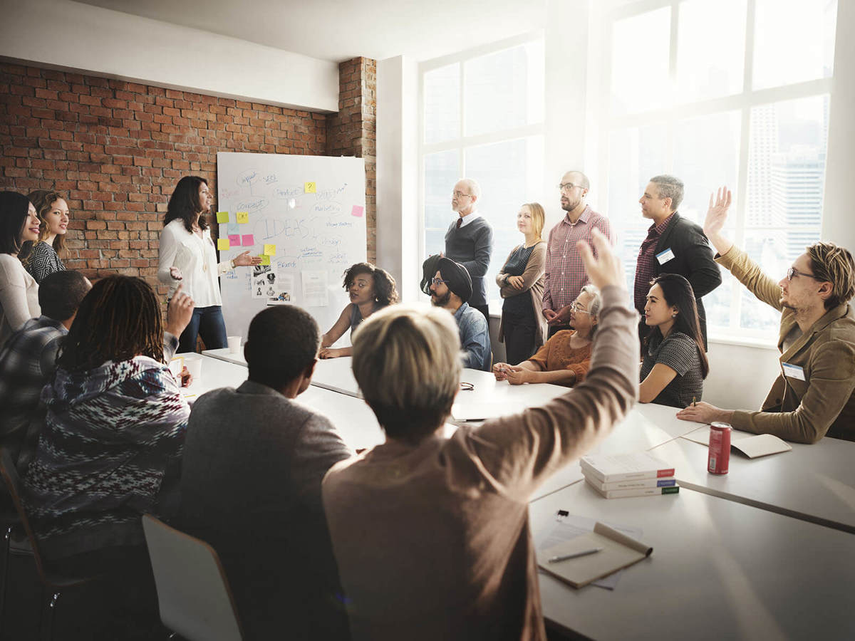 people raising their hands in a meeting room
