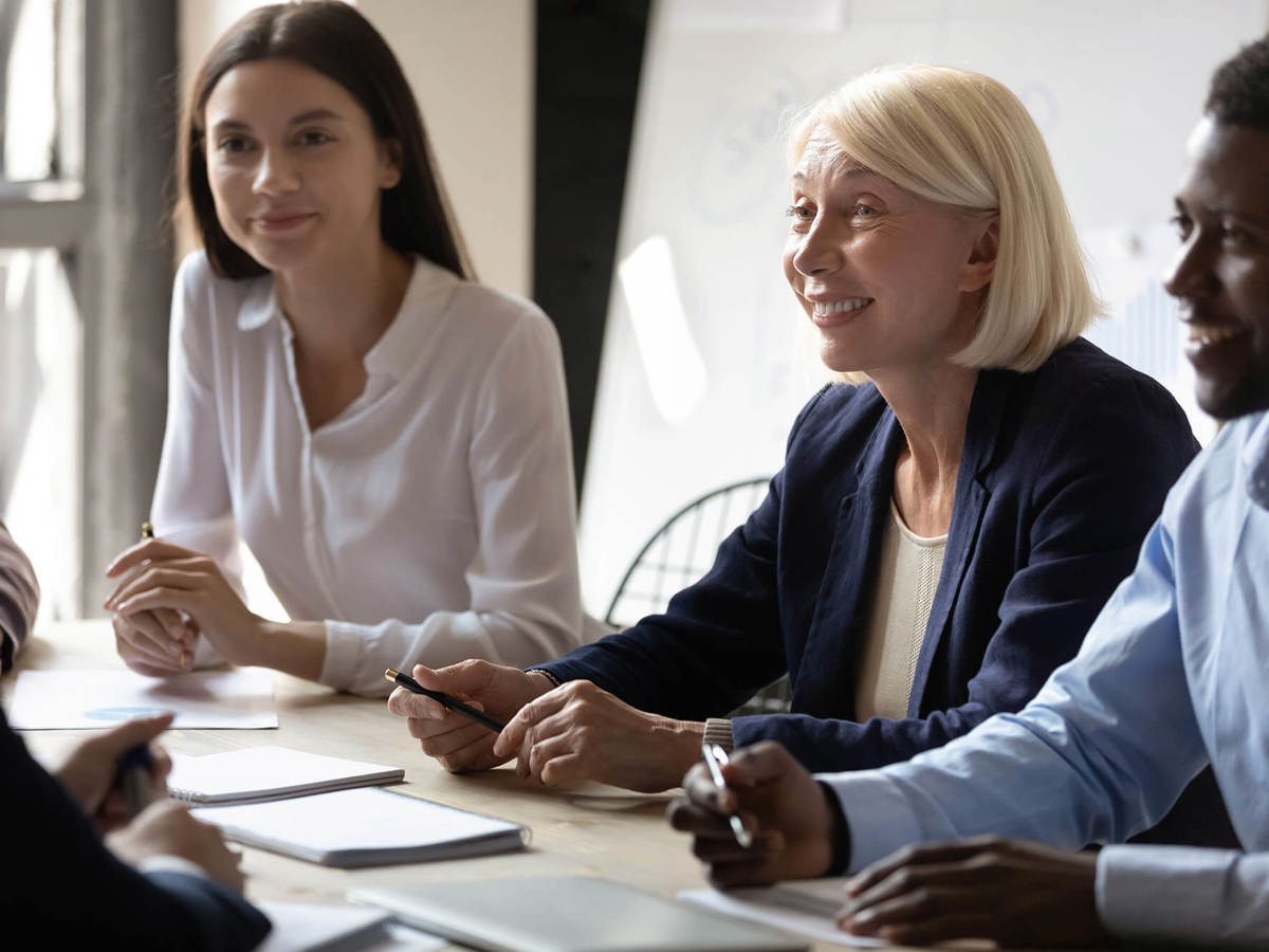 two ladies and a man smiling in a meeting