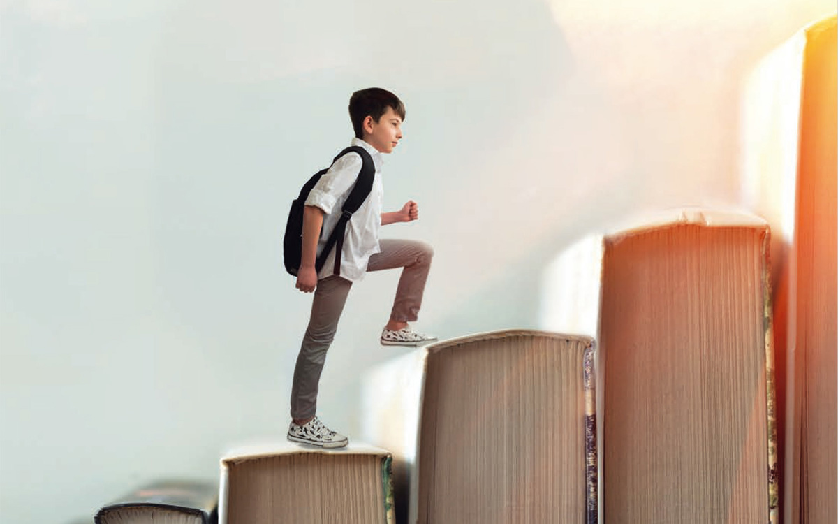 Child climbing stairs made of books