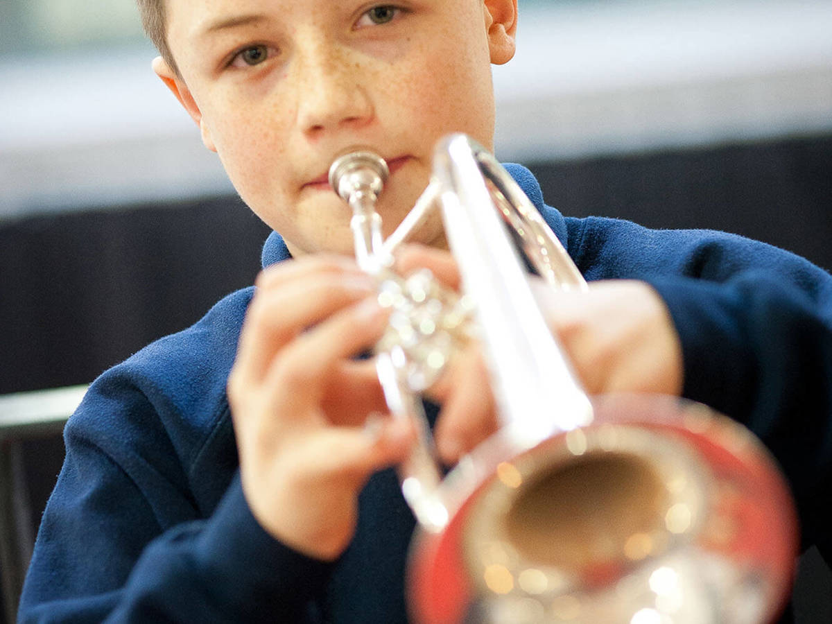 Pupils-learning young boy playing the trumpet 