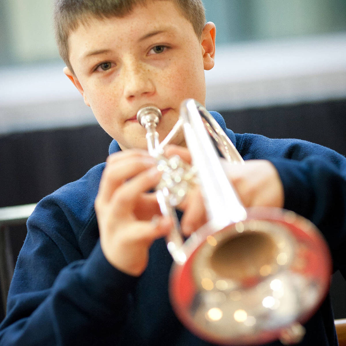 Pupils-learning young boy playing the trumpet