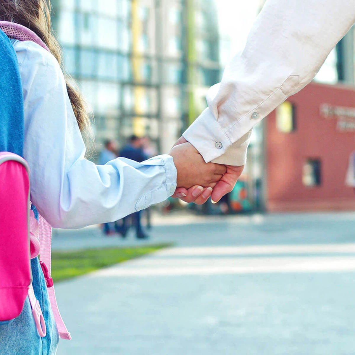 school-environment pupil and their guardian holding hands walking towards a school