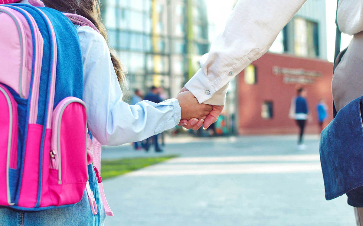 school-environment pupil and their guardian holding hands walking towards a school
