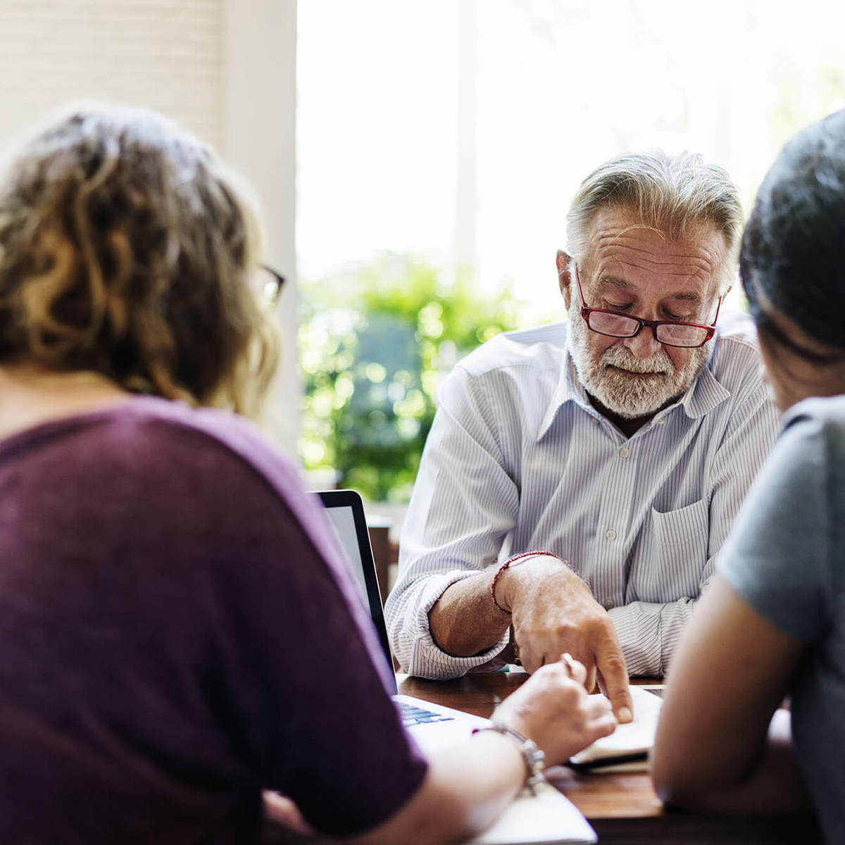 Man pointing at a word on his document in a meeting  with two others