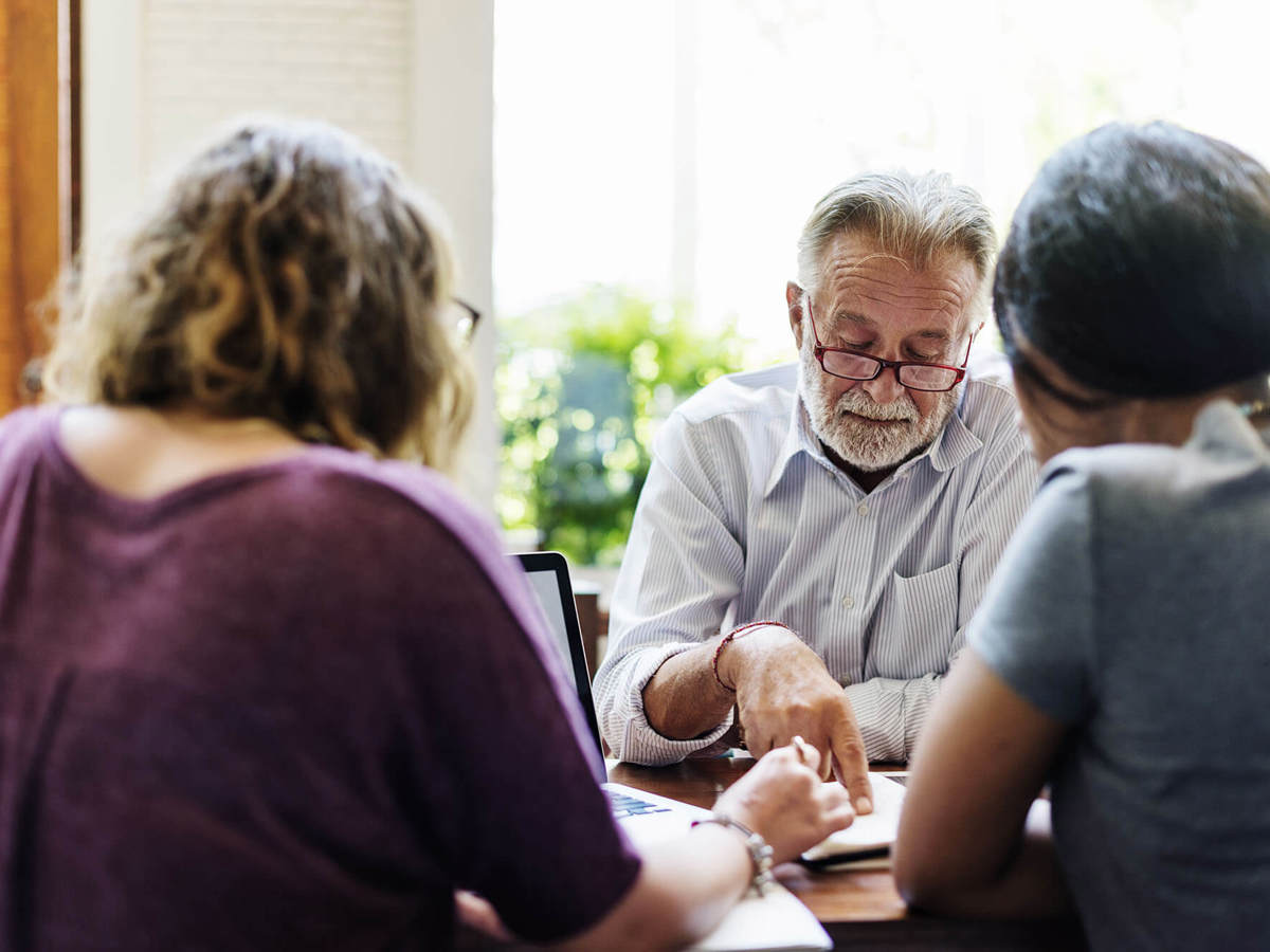 Man pointing at a word on his document in a meeting  with two others