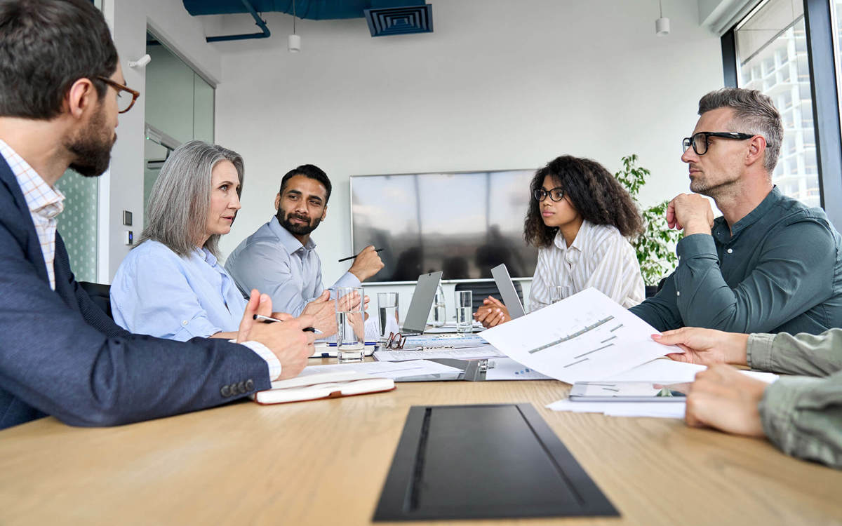 people in meeting looking across each other  at table