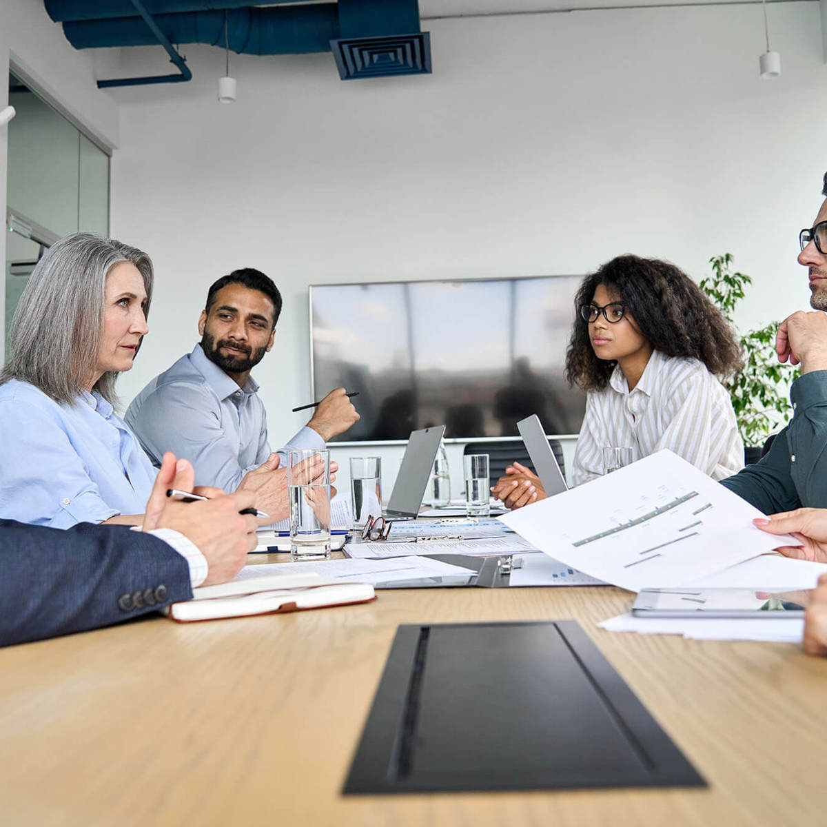 people in meeting looking across each other  at table