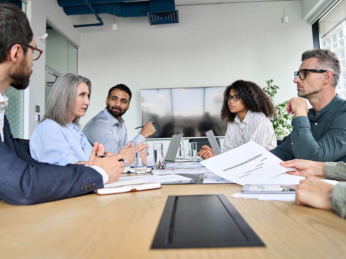 people in meeting looking across each other  at table