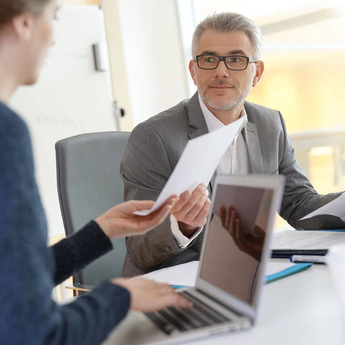 two people exchanging documents in a meeting