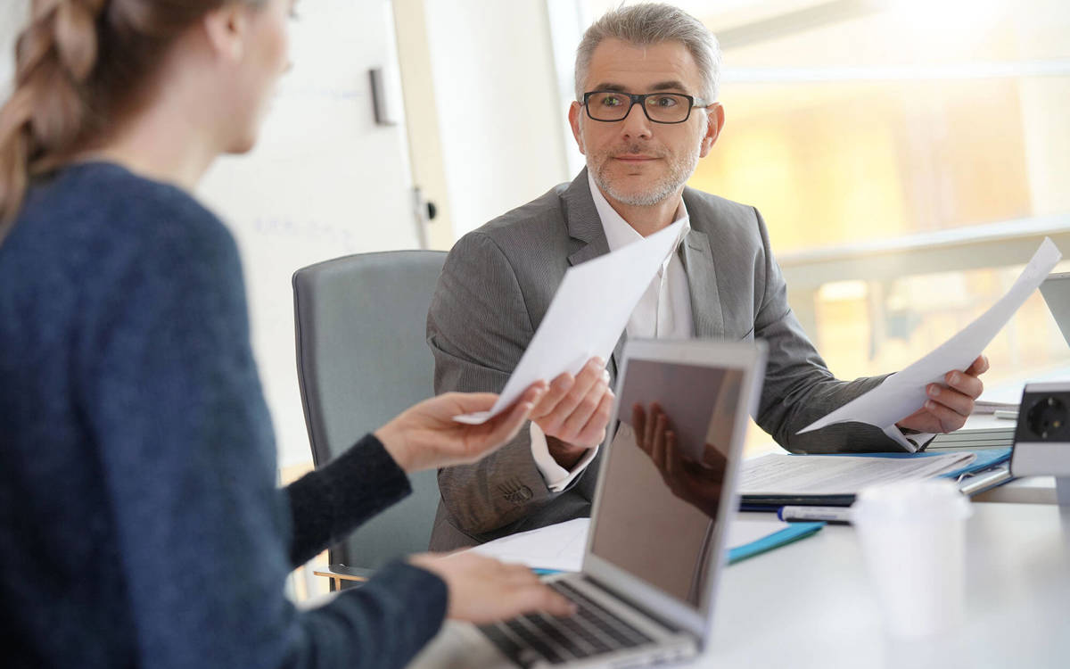 two people exchanging documents in a meeting