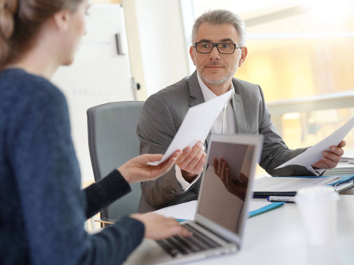 two people exchanging documents in a meeting