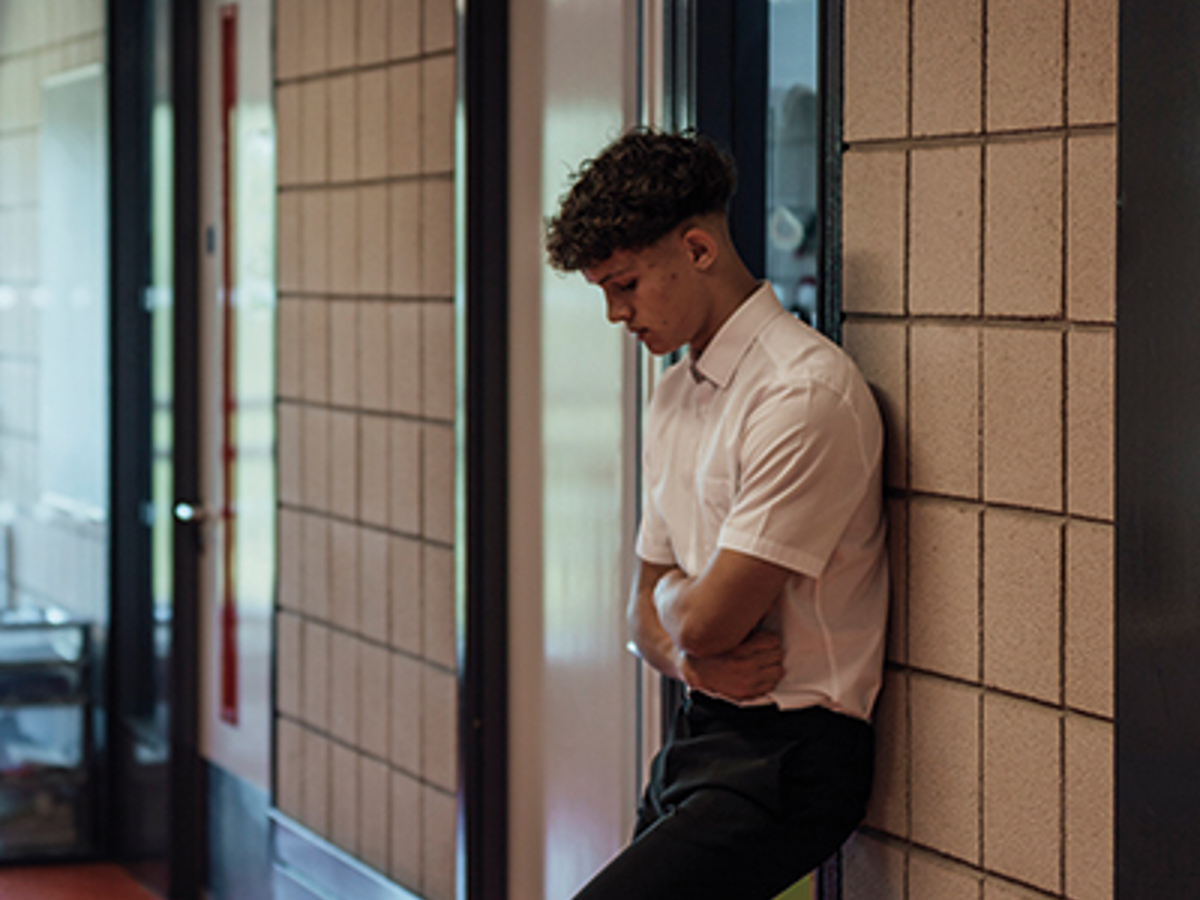 Male student stands alone in a school corridor