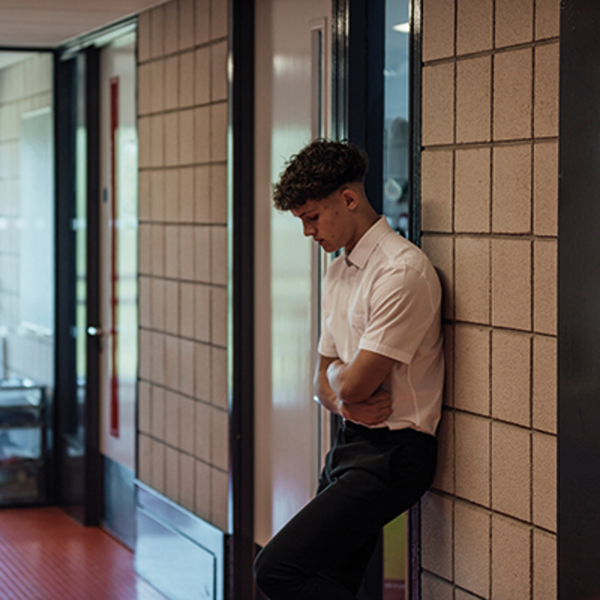 Male student stands alone in a school corridor