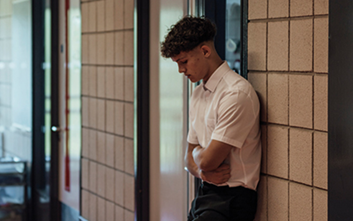 Male student stands alone in a school corridor