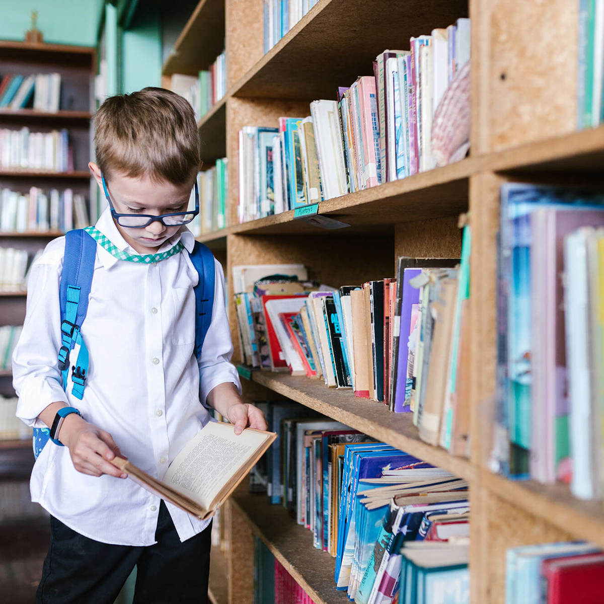 Pupils-learning young pupil checking out a book in the library