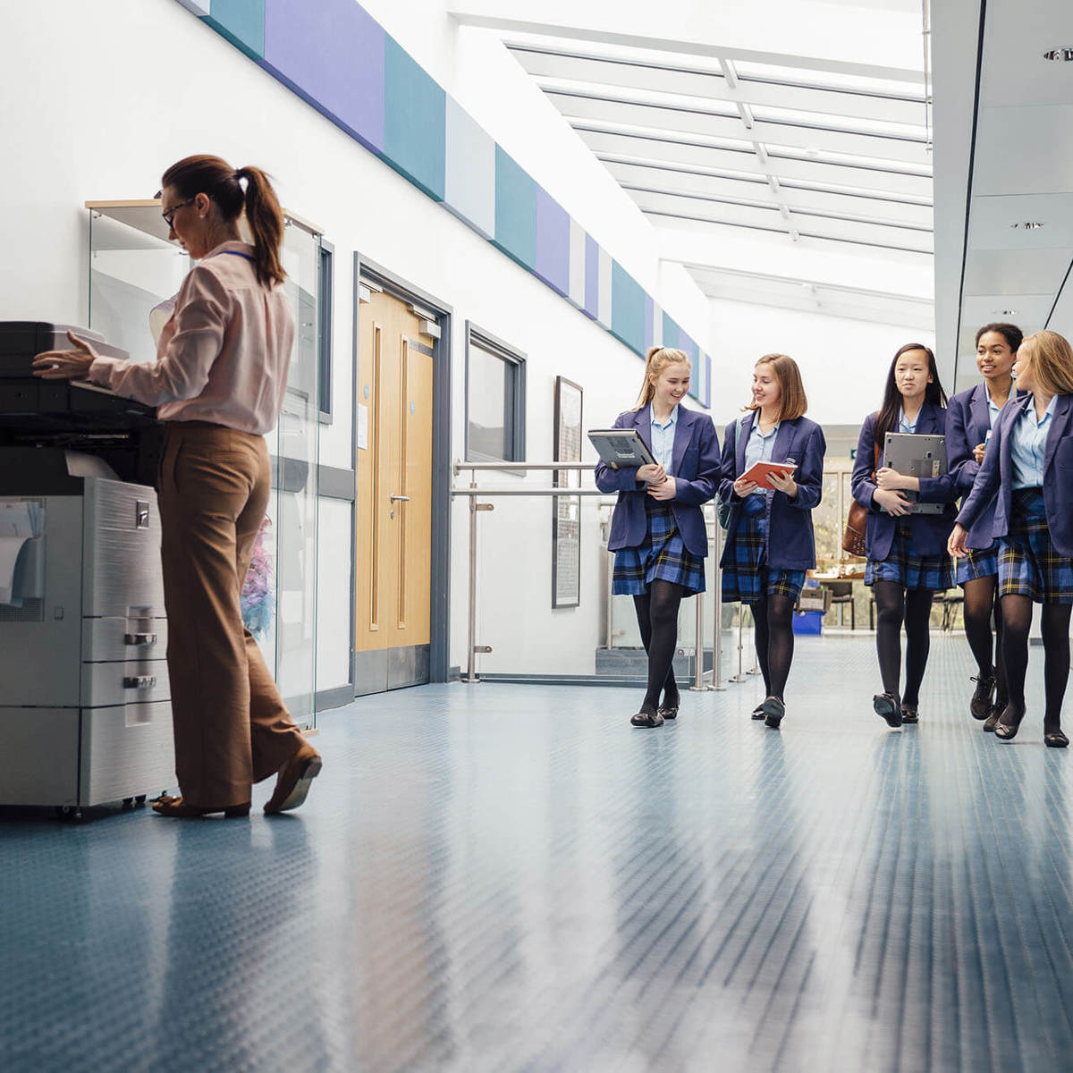 school-environment group of pupils walking down corridor with teacher using the printer