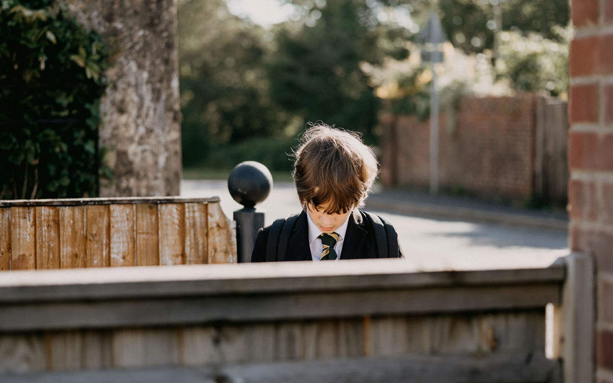 school-environment boy looking down outside near some fences