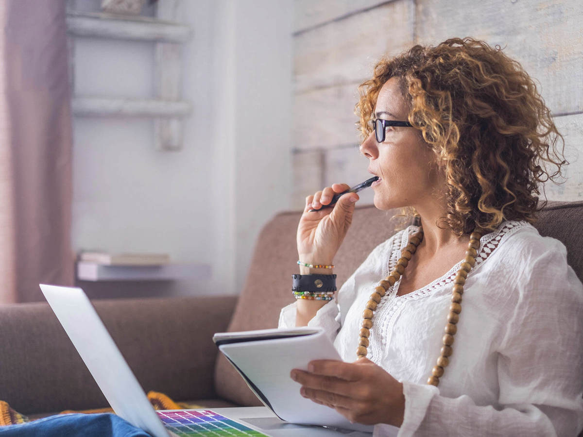 people woman thinking with her laptop on her lap holding pen and paper